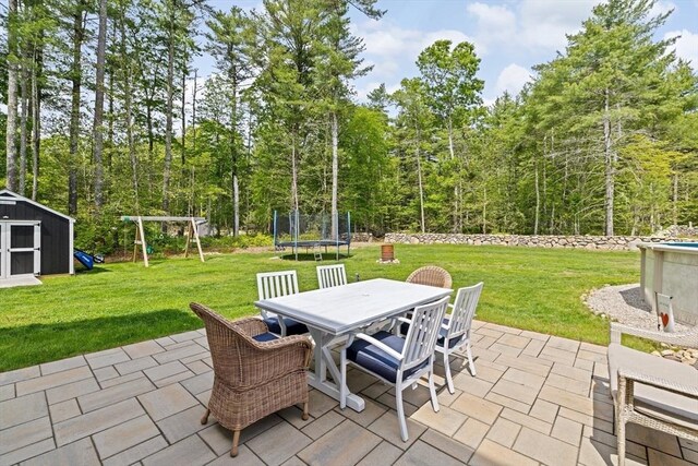 111 Spruce St, Middleboro, MA 02346 - view of patio with a trampoline, outdoor dining space, a playground, and a view of trees