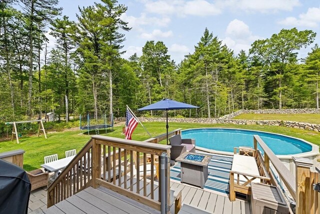 111 Spruce St, Middleboro, MA 02346 - swimming pool featuring a trampoline, a wooden deck, a lawn, a playground, and a fire pit