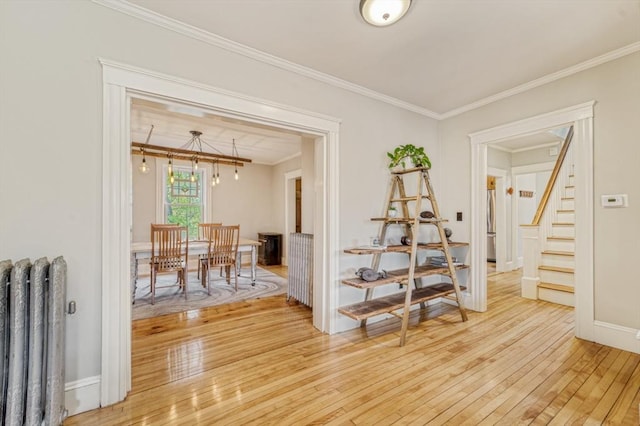 hallway featuring light wood-type flooring, stairs, crown molding, and radiator heating unit