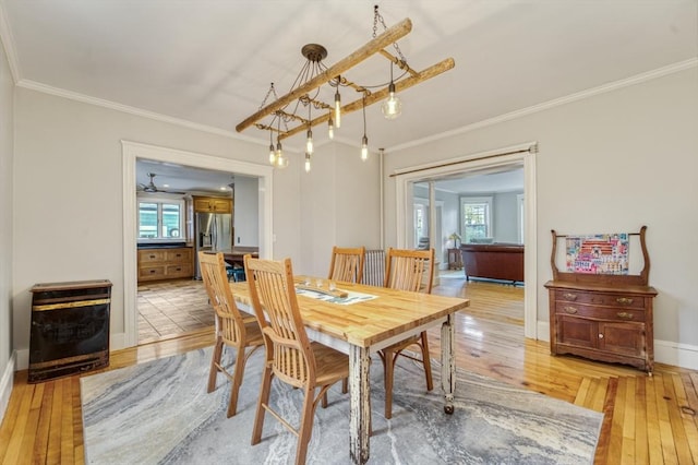 dining space with light wood-style floors, baseboards, and ornamental molding
