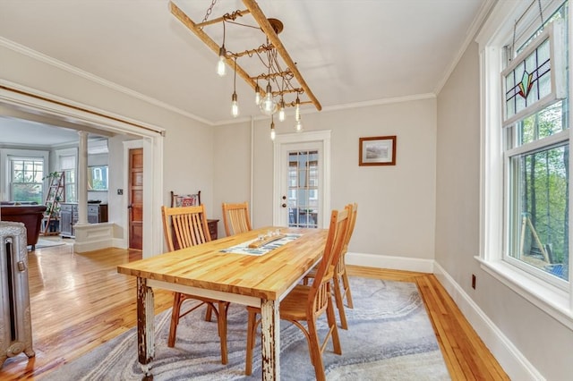 dining room featuring crown molding, baseboards, plenty of natural light, and light wood-style floors