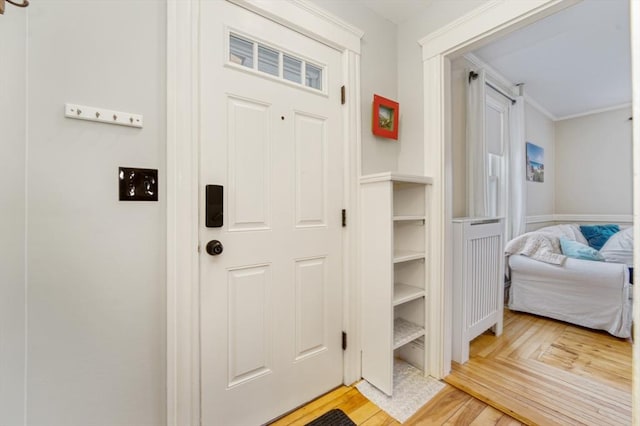 entryway featuring ornamental molding and light wood-style floors