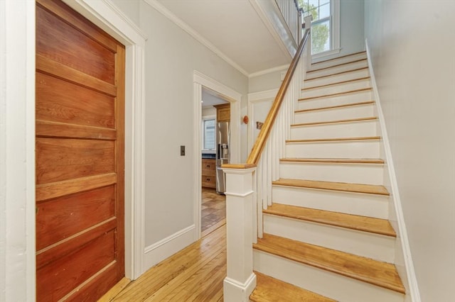 staircase featuring crown molding, baseboards, and wood finished floors