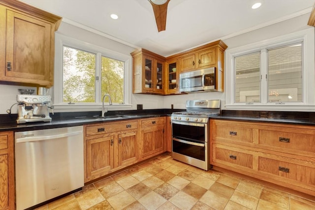 kitchen with a sink, dark countertops, stainless steel appliances, and brown cabinets