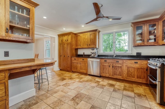 kitchen featuring crown molding, ceiling fan, a sink, brown cabinetry, and stainless steel appliances