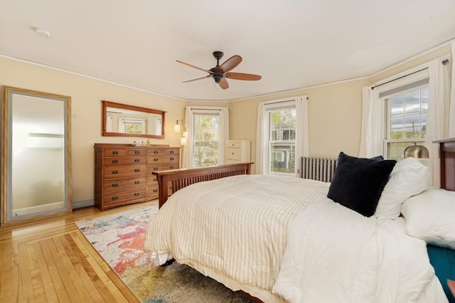bedroom with crown molding, baseboards, ceiling fan, and light wood-type flooring