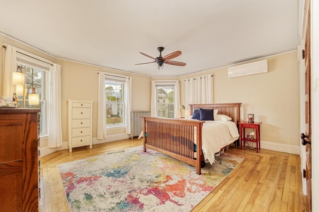 bedroom featuring baseboards, a wall mounted air conditioner, light wood finished floors, and multiple windows