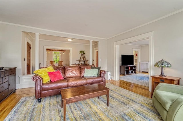 living room featuring crown molding, baseboards, decorative columns, and light wood finished floors