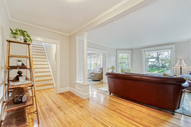 living area with ornamental molding, decorative columns, and light wood-style flooring
