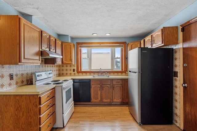 kitchen with black dishwasher, white electric stove, light countertops, freestanding refrigerator, and a sink