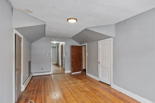 bonus room featuring vaulted ceiling, baseboard heating, wood finished floors, and baseboards