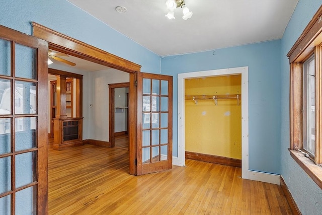 hallway with light wood-type flooring, baseboards, and french doors