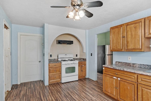 kitchen featuring brown cabinetry, white gas range, dark wood finished floors, and freestanding refrigerator