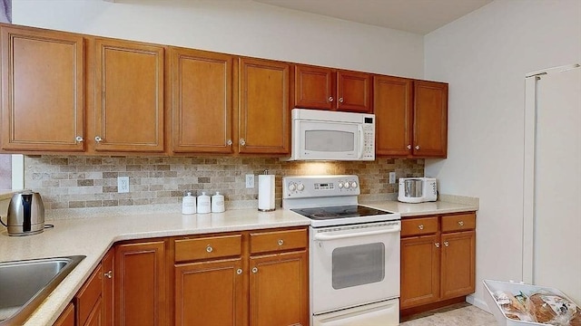 kitchen featuring brown cabinets, decorative backsplash, and white appliances