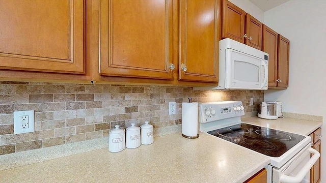 kitchen featuring backsplash, brown cabinets, light countertops, and white appliances