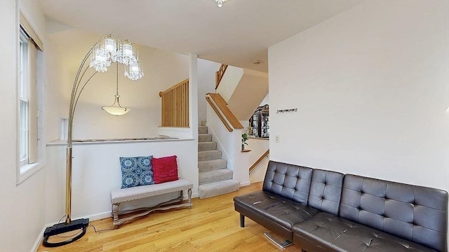 living room with baseboards, an inviting chandelier, wood finished floors, and stairs