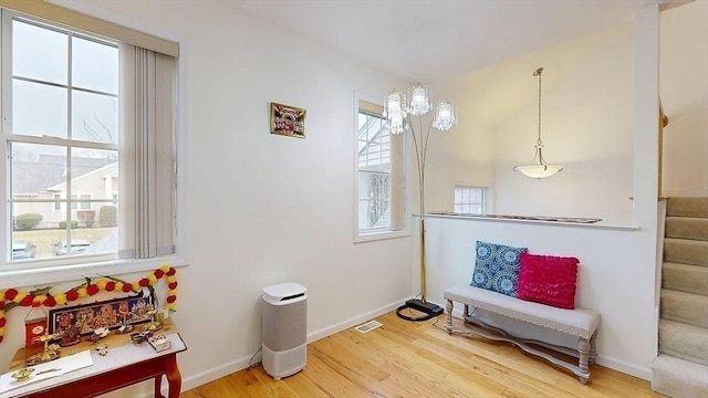 sitting room with plenty of natural light, stairway, light wood-type flooring, and baseboards