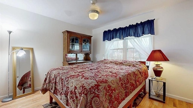 bedroom with light wood-type flooring, baseboards, and a ceiling fan