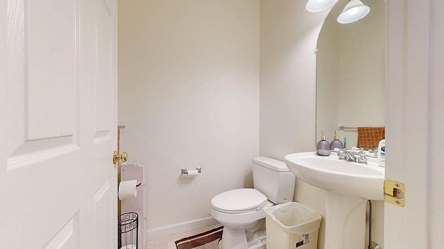 half bath featuring a sink, toilet, and baseboards