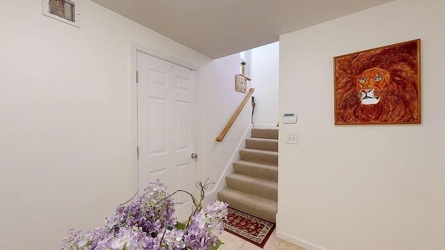 stairway with visible vents, baseboards, and tile patterned floors
