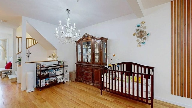 bedroom with beamed ceiling, an inviting chandelier, and wood finished floors
