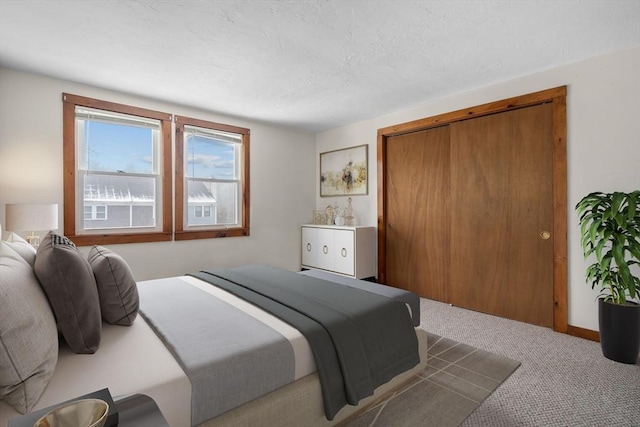 carpeted bedroom with a textured ceiling and a closet