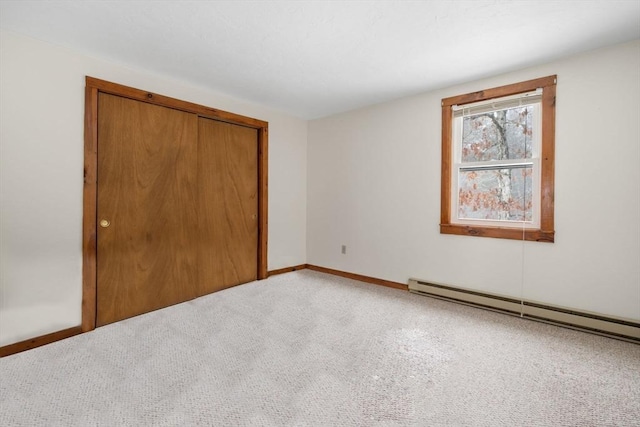 unfurnished bedroom featuring carpet flooring, a closet, and a baseboard heating unit