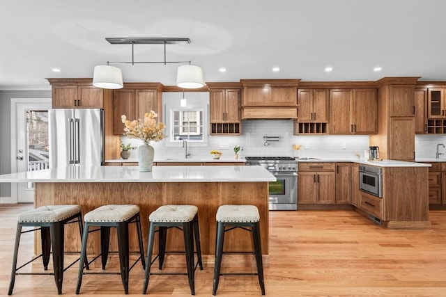 kitchen featuring a kitchen island, decorative light fixtures, sink, a kitchen bar, and premium appliances