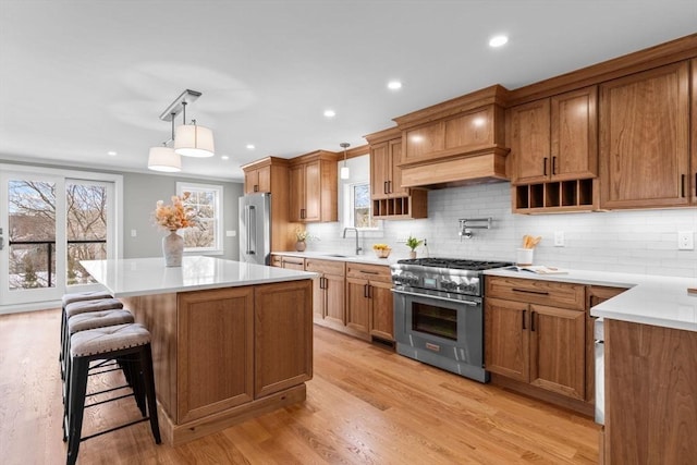 kitchen featuring pendant lighting, sink, premium appliances, a center island, and light hardwood / wood-style floors