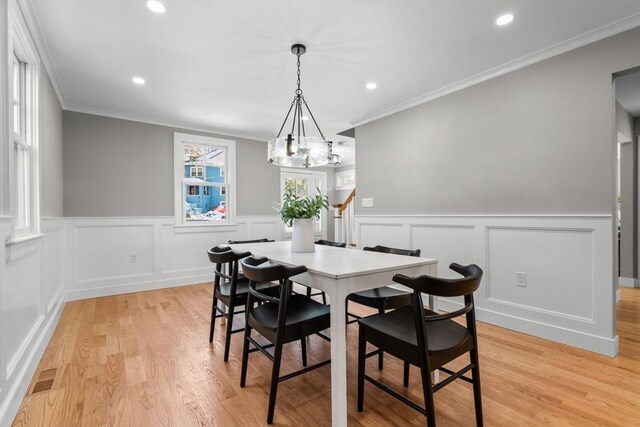 dining space featuring a notable chandelier, ornamental molding, and light hardwood / wood-style floors