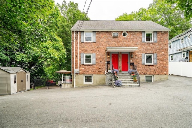 10-12 Spring Rd, Arlington, MA 02476 - view of front facade with brick siding, a storage shed, a gate, and an AC wall unit
