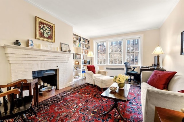 living room featuring built in shelves, radiator heating unit, ornamental molding, a fireplace, and hardwood / wood-style flooring