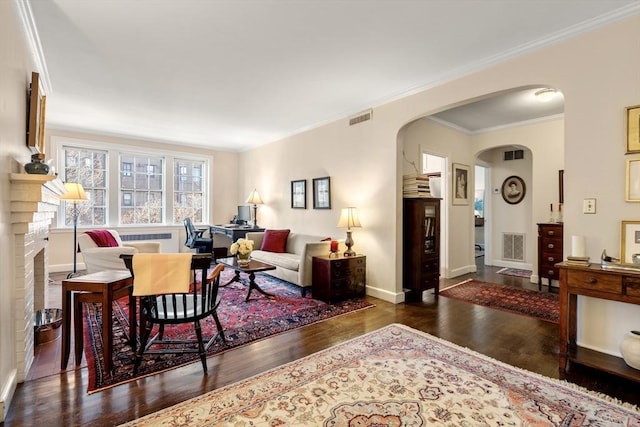 living room with ornamental molding, a fireplace, and dark wood-type flooring