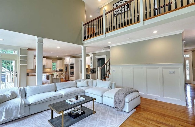 19 Mulberry Ln, Franklin, MA 02038 - living area with ornate columns, a towering ceiling, crown molding, light wood-type flooring, and a decorative wall