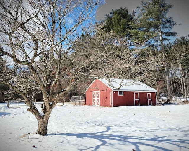 yard covered in snow with an outbuilding and fence