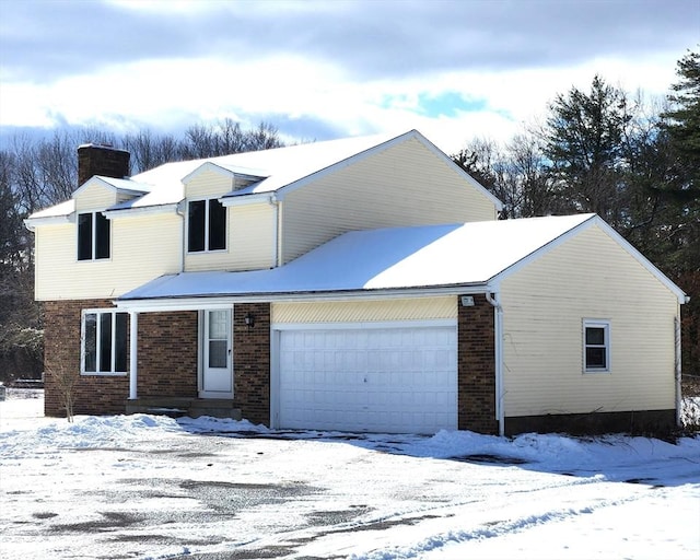 traditional-style home with a garage, a chimney, and brick siding