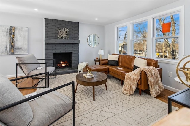 interior space with recessed lighting, a brick fireplace, baseboards, and wood finished floors