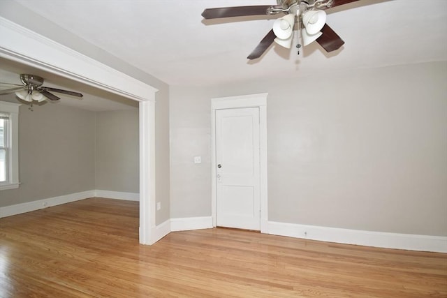empty room featuring ceiling fan, light wood finished floors, and baseboards
