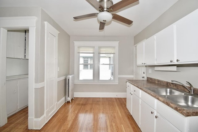 kitchen featuring radiator, a sink, light wood-style floors, and a ceiling fan
