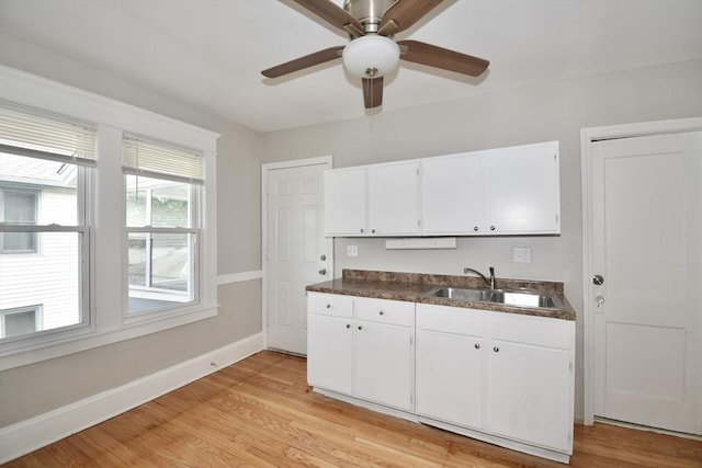 kitchen featuring a sink, dark countertops, white cabinets, and a ceiling fan