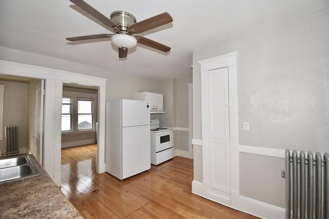 kitchen featuring radiator heating unit, white appliances, a ceiling fan, and light wood finished floors