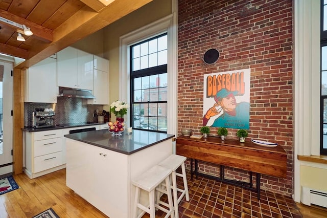 kitchen featuring white cabinetry, a baseboard radiator, wood-type flooring, and beamed ceiling