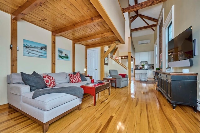 living room featuring a high ceiling, light wood-type flooring, wood ceiling, and beamed ceiling