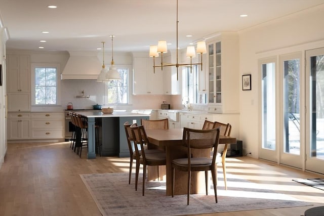 dining room featuring light wood-style floors, crown molding, a notable chandelier, and recessed lighting