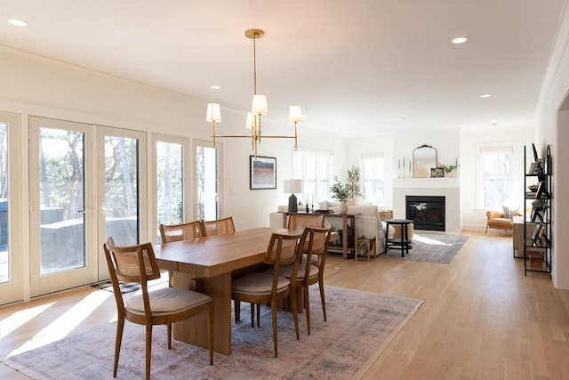 dining space with a glass covered fireplace, plenty of natural light, light wood-style flooring, and recessed lighting