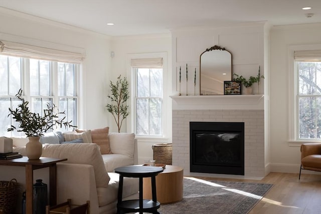 living area featuring crown molding, recessed lighting, a brick fireplace, wood finished floors, and baseboards