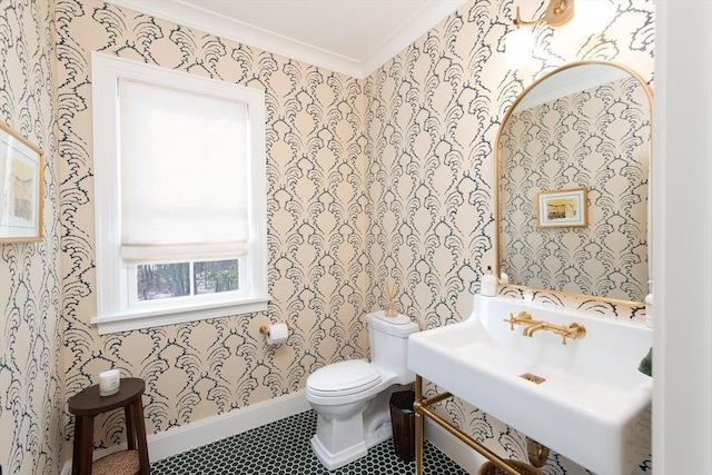 half bathroom featuring wallpapered walls, baseboards, toilet, tile patterned flooring, and a sink