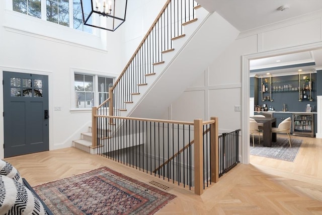 foyer entrance featuring beverage cooler, a towering ceiling, a wealth of natural light, and a decorative wall