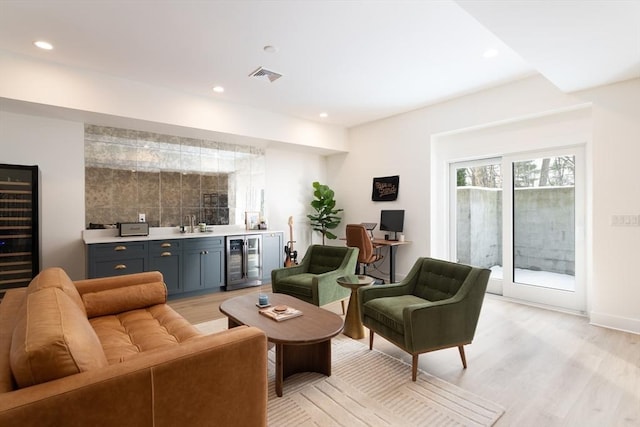 living room with beverage cooler, indoor wet bar, visible vents, and light wood-style floors