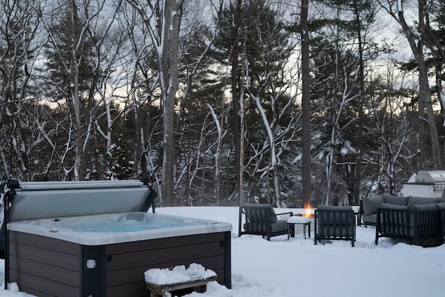 yard layered in snow featuring an outdoor living space with a fire pit and a hot tub